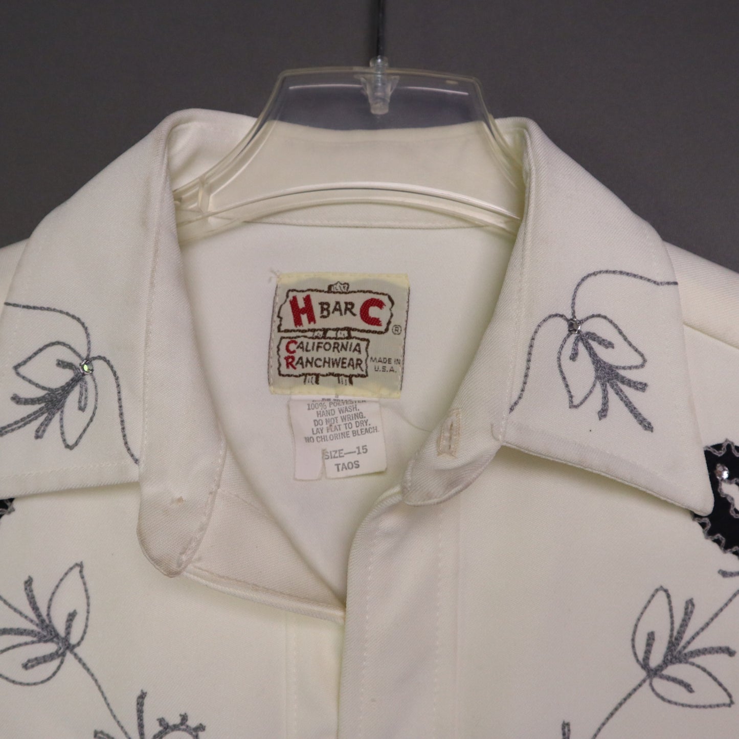 This vintage 1970s H Bar C California Ranchwear "Taos" cream polyester fabric, white fringe detailing, and black and gray floral embroidery with pearl snap