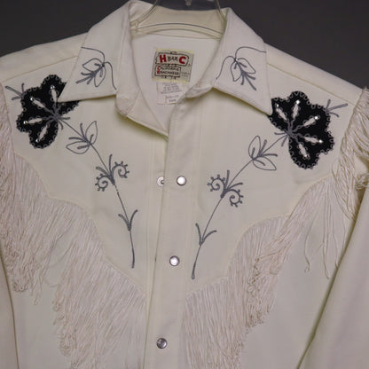 This vintage 1970s H Bar C California Ranchwear "Taos" cream polyester fabric, white fringe detailing, and black and gray floral embroidery with pearl snap