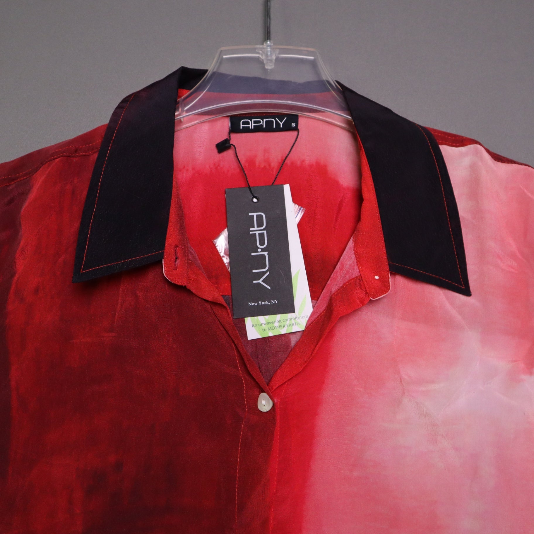APNY brand button-up shirt features a vibrant red and pink gradient tie-dye pattern and a contrasting dark collar