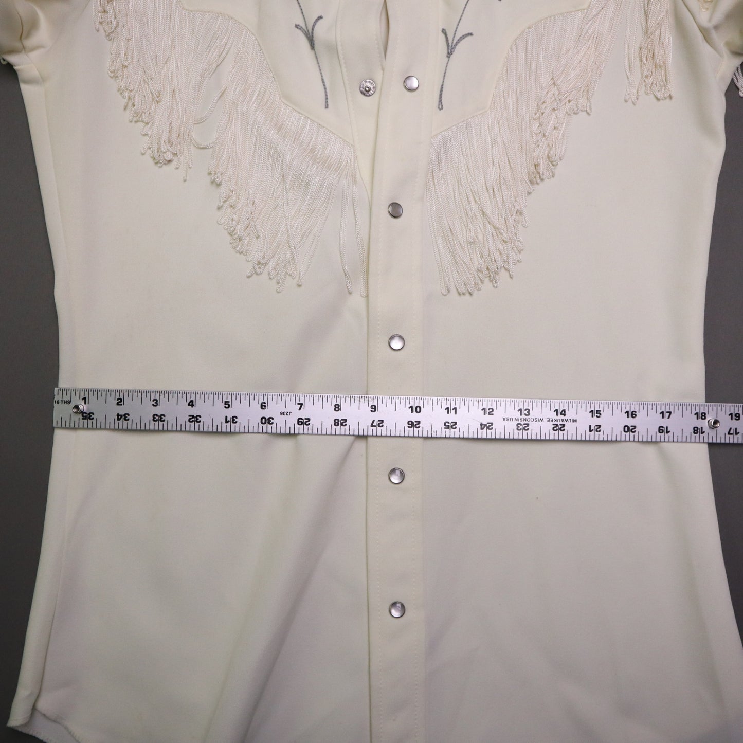This vintage 1970s H Bar C California Ranchwear "Taos" cream polyester fabric, white fringe detailing, and black and gray floral embroidery with pearl snap