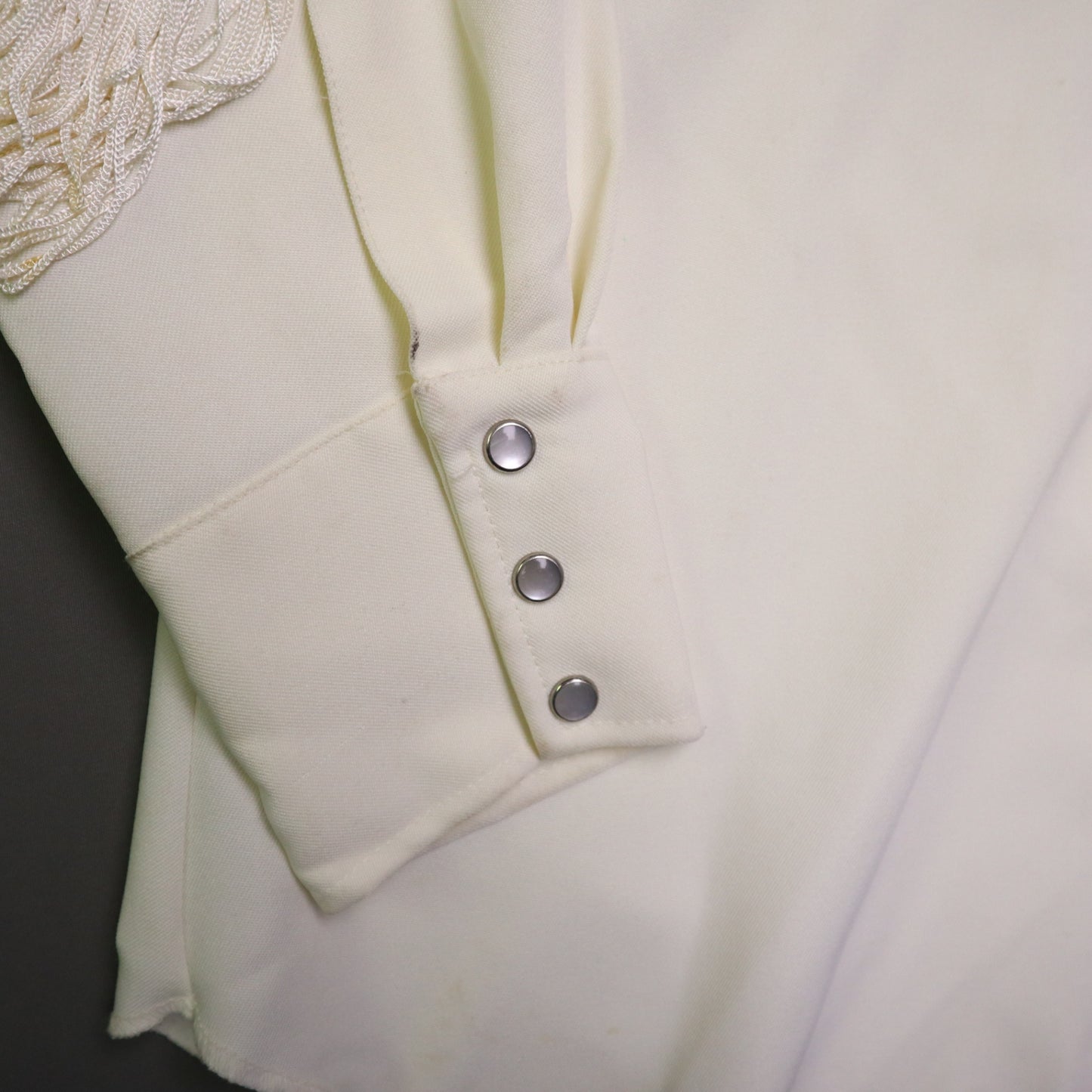 This vintage 1970s H Bar C California Ranchwear "Taos" cream polyester fabric, white fringe detailing, and black and gray floral embroidery with pearl snap