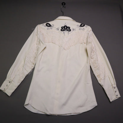 This vintage 1970s H Bar C California Ranchwear "Taos" cream polyester fabric, white fringe detailing, and black and gray floral embroidery with pearl snap