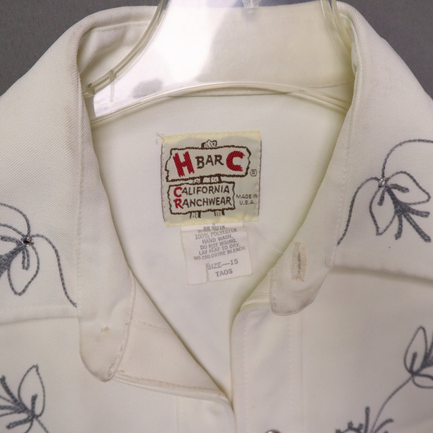 This vintage 1970s H Bar C California Ranchwear "Taos" cream polyester fabric, white fringe detailing, and black and gray floral embroidery with pearl snap